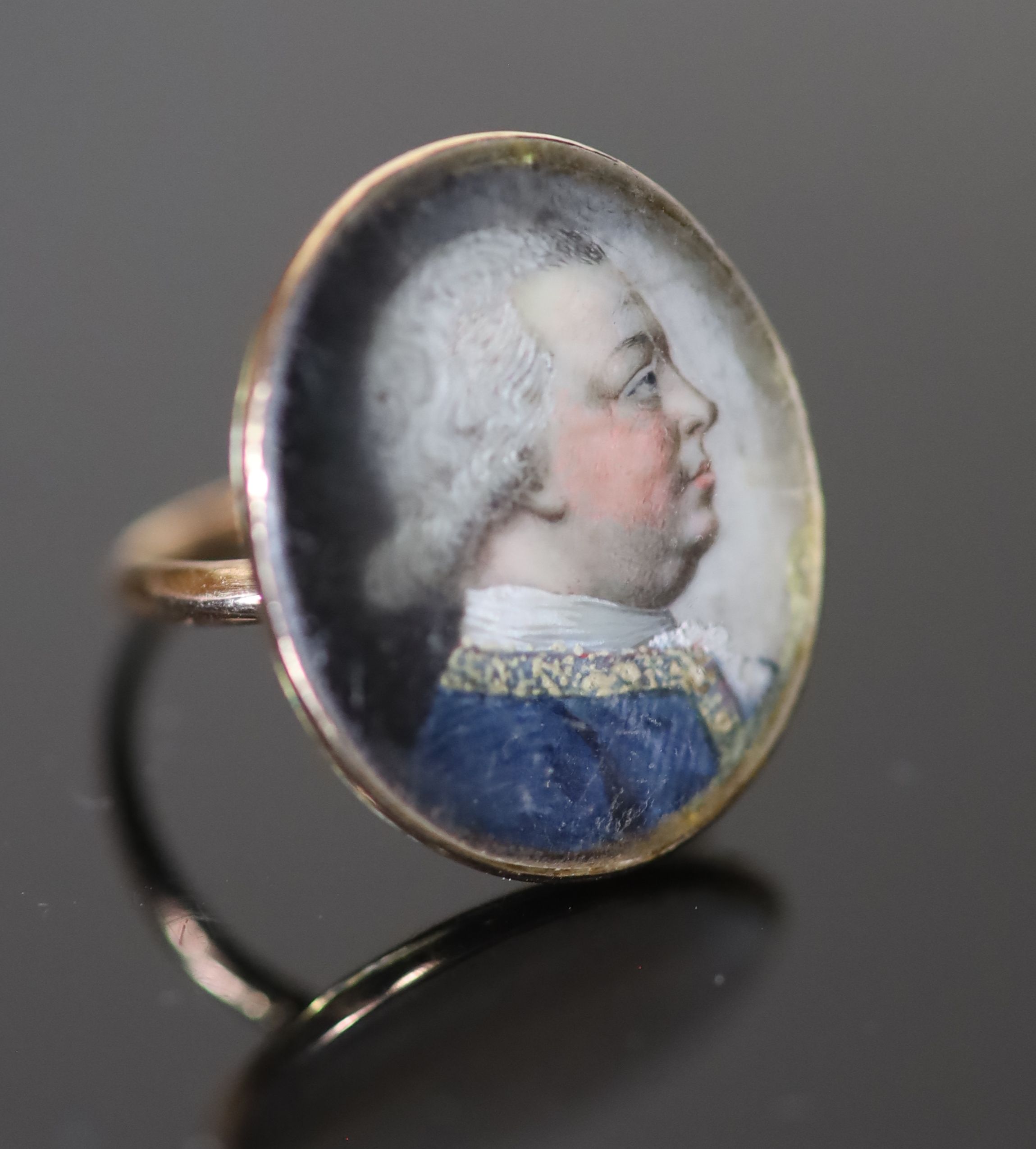 A George III gold and inset oval portrait miniature ring, painted with the bust of a gentleman to sinister,
